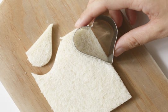 サンドウィッチ用の薄切り食パンを、下写真のようにハート型の半分部分で型抜きする。それを、表面にこげ目が つかないように軽く焼き、割り箸 で目をあけて、おばけクルトン風に。 オレンジパプリカやハムも、かぼちゃやコウモリ形に抜いてトッピングしてでき上がり。「葉野菜トレビスを使うと紫 色で不気味度がアップします」