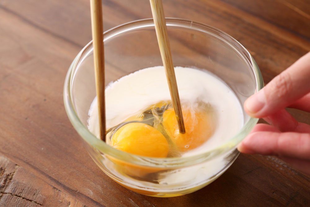 卵に牛乳を入れて溶きほぐすところ