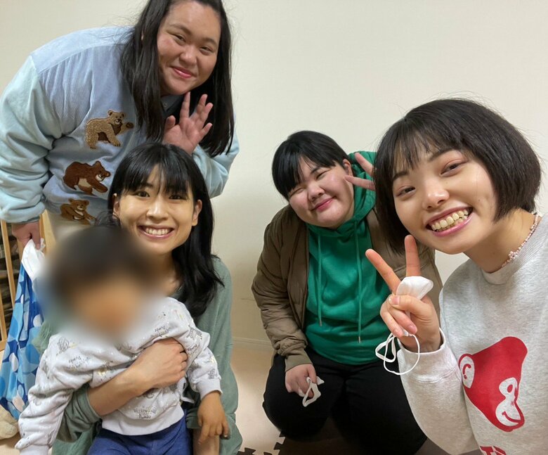 息子さんを抱く酒寄さんとぼる塾のメンバー（左奥から田辺智加さん、あんりさん、きりやはるかさん）