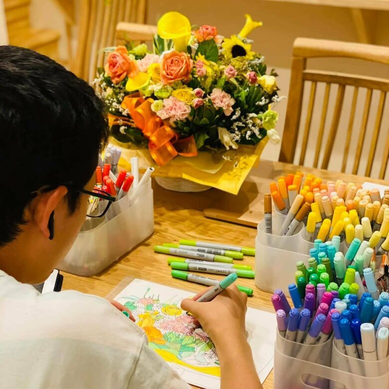 ロイヤルホストのコースターデザインに採用された「私の花束」の絵を描く貫太さん