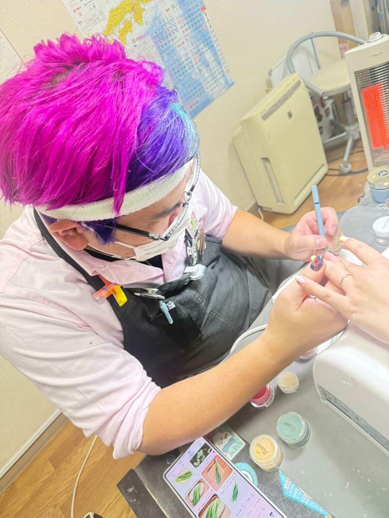 ビビッドカラーの髪色もトレードマーク。施術中の塩見さん