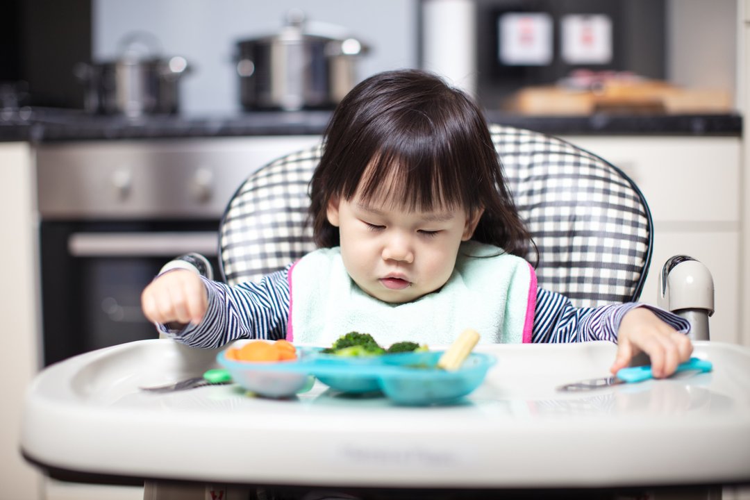 baby girl falling asleep when eating on high chair at home