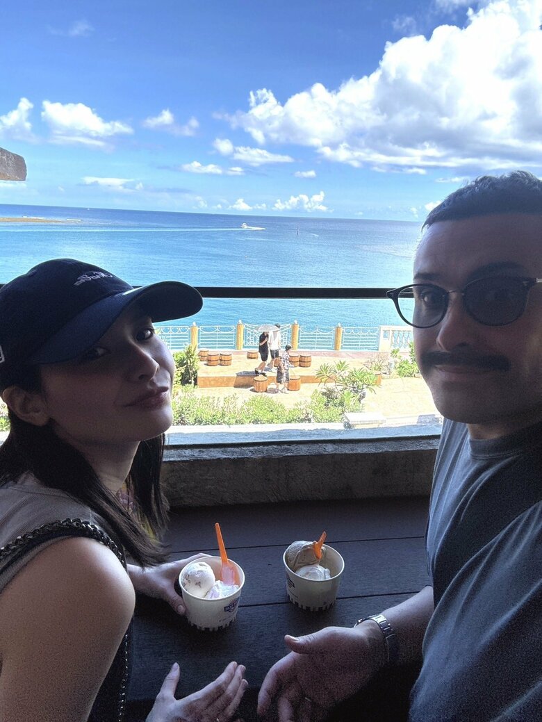 沖縄ブルーの海をバックにおいしそうなアイスに舌鼓を打つ植野さん・比嘉さんご夫婦