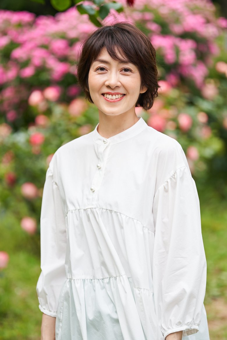 ピンク色の花に囲まれる駒村さん