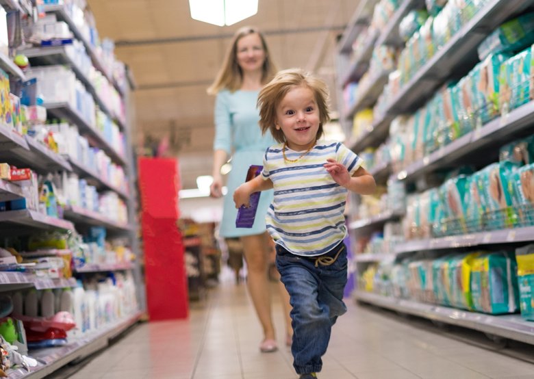 Cute little boy running from his mother in the store