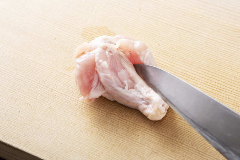 鶏肉は骨に沿って切り込みを入れる（※）。豆腐は4等分にし、ごぼうはささがきにする。万能ねぎは小口切りにし、にんにくは包丁の背などで潰す。

※皮目を下にして、骨の脇２箇所に切り込みを入れることで味が染み込みやすく、火の通りも早くなり、食べやすくなる。あまり深く切りすぎると骨から肉が取れてしまうので、骨が見えればOK。