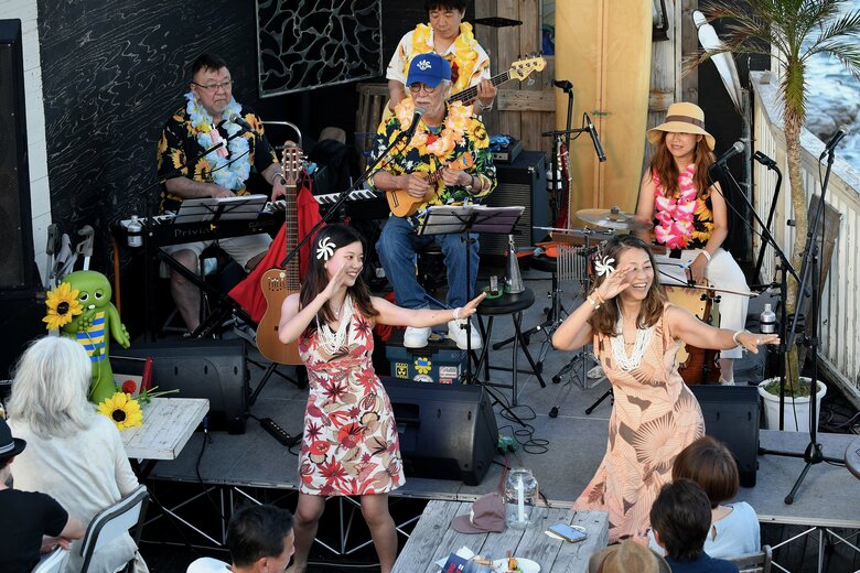 5年前、逗子の海辺のライブ会場でマイク眞木さん（後方の青いキャップの方）の演奏に合わせて娘・花さん（前方・中央）とフラを披露する加奈子さん（前方・右）