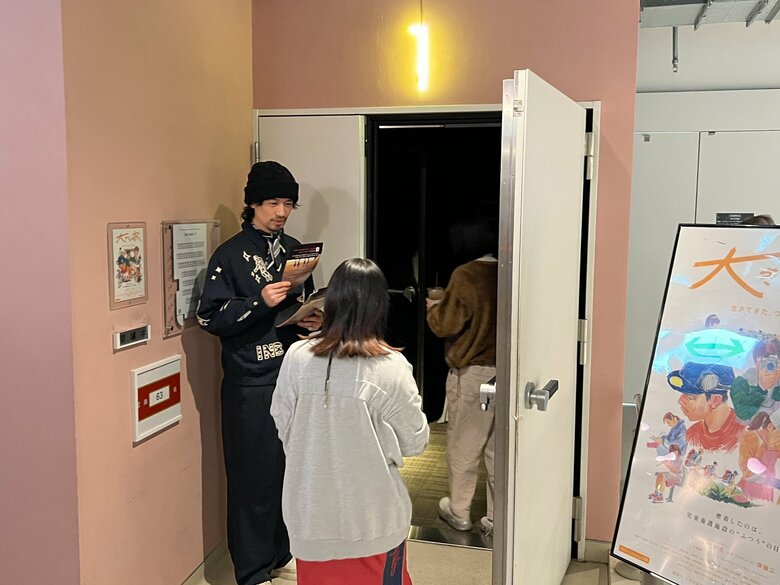 映画館で観客にチラシを手渡しする齊藤さん