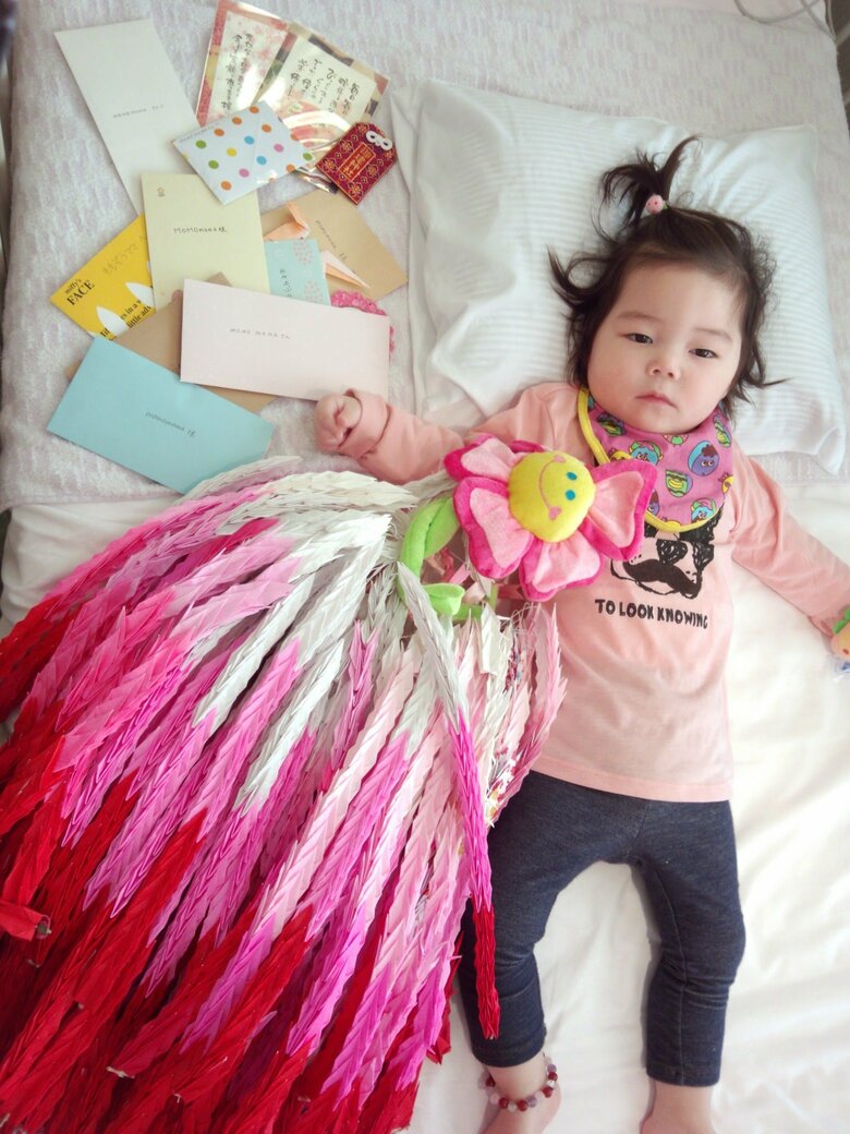 オペ前に友だちが作ってくれた3000羽鶴と一緒に。1歳の萌々花さん