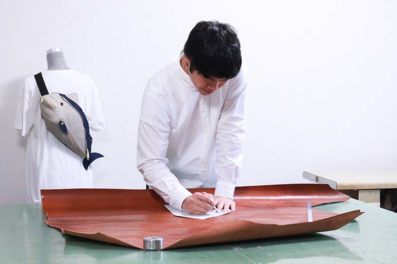 裁断のため、型紙を革にうつす川本さん