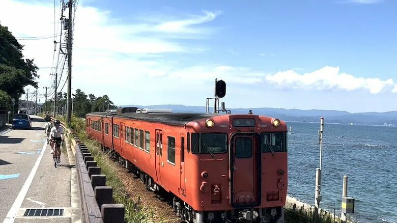富山県のJR氷見線 雨晴駅近くの海岸線を自転車で走る山口さん