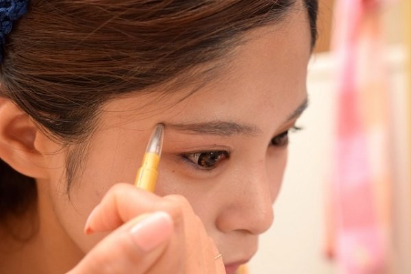 眉毛を描く女性の画像