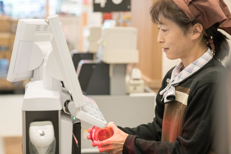 Supermarket clerk using a digital cash register and check-out system