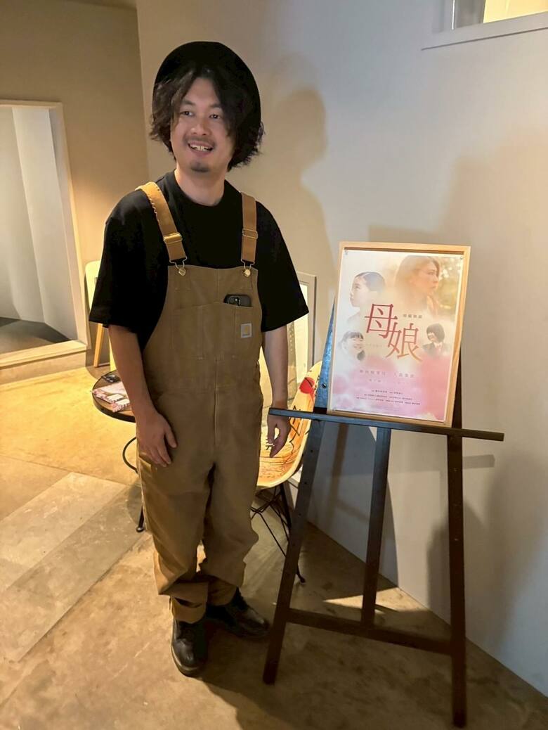 西坂さんが監督した短編映画『母娘―おやこ―』の看板と一緒に