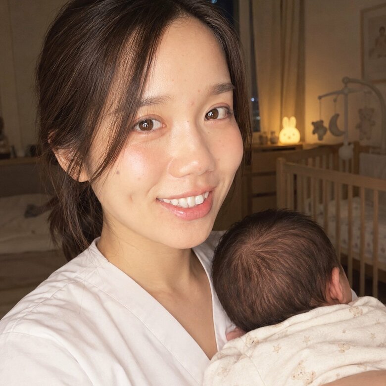 優しい明かりのなか、助産師の城野院長の腕の中ですやすや眠る赤ちゃん