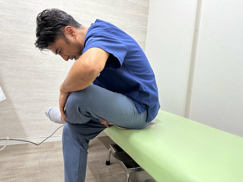 成長痛や足の痛みを防ぐストレッチ②いすなどに腰掛けて左足を右膝に乗せ、上半身をかがめることで左太ももの裏の筋肉を伸ばす。反対側も同様に