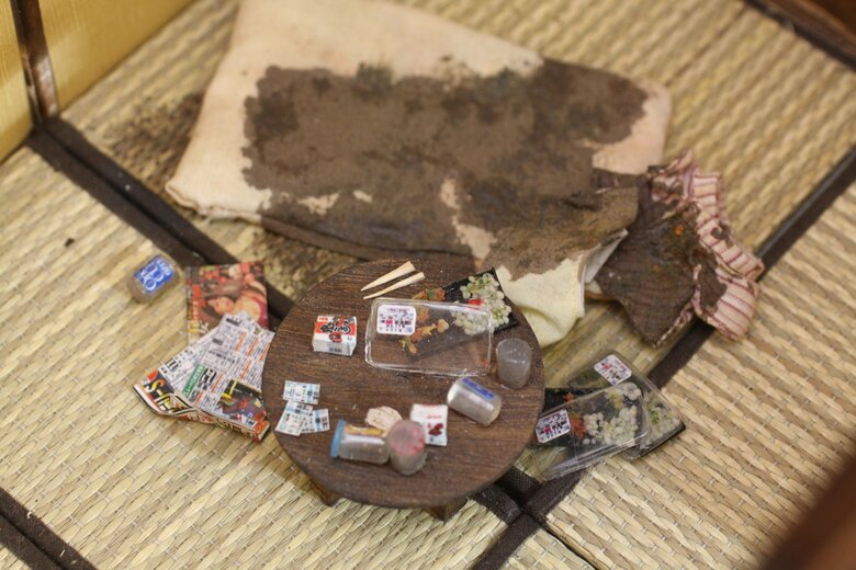 中高年男性の孤独死現場を表現したミニチュア。布団の上で亡くなったであろう痕跡が残っています