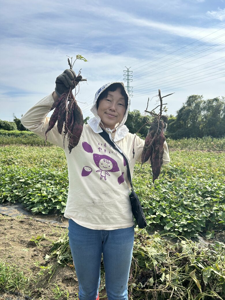 収穫したサツマイモを手に笑顔の阿佐美やいも子さん