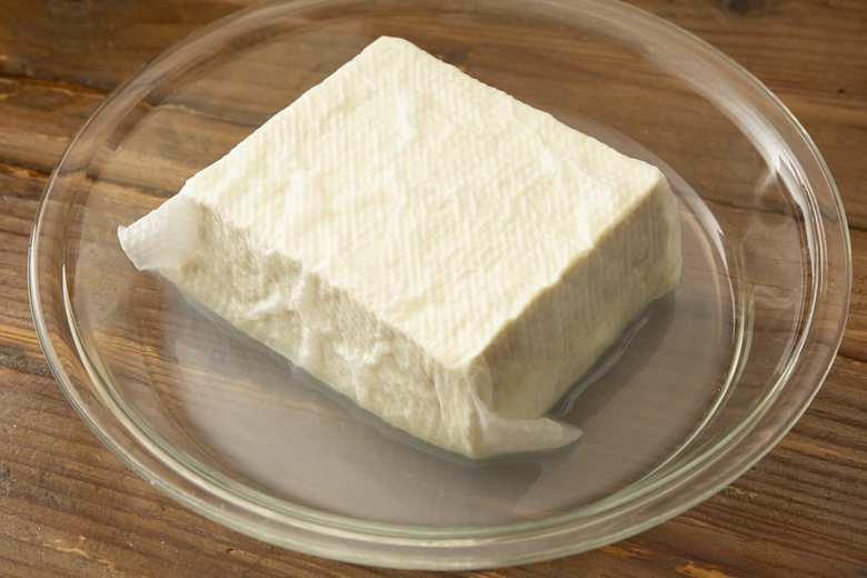 豆腐はキッチンペーパーで包み、耐熱容器に入れる。ラップをしないで電子レンジ600Wで2〜3分加熱する。そのまま5分ほどおいて出てきた水分を捨て、1.5〜2cm角に切る。