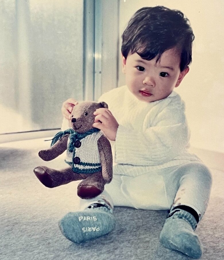 育ての両親からもらって大切にしていたクマのぬいぐるみを持つ1、2歳のころの志村さん