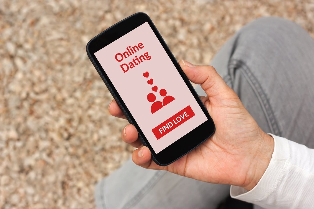 Hand holding smartphone with online dating app mock up on screen. All screen content is designed by me