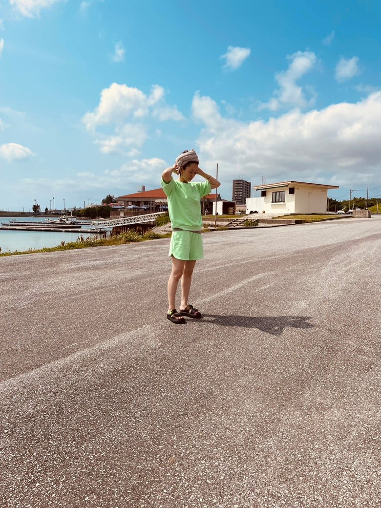 青空に映えるグリーンのセットアップ姿で佇む島袋さん。すごく健康的！