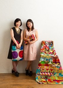 「柄が素敵ですね！」母娘の起業で挑む「アフリカンプリント」の生地で作ったタベストリーとバッグを持った仲本さん親子