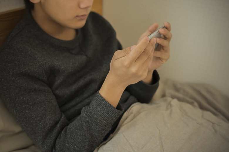 ベッドでスマホを見る子ども