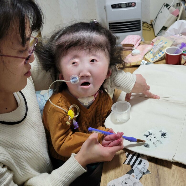 支援学校の冬休みの宿題でトートバックの絵付けをしている