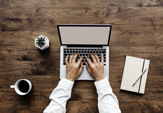 Aerial view of a man using computer laptop on wooden table