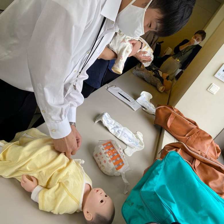 「育児研修」の様子。新入社員が慣れない手つきで赤ちゃんの着替えやおむつ替えを体験。