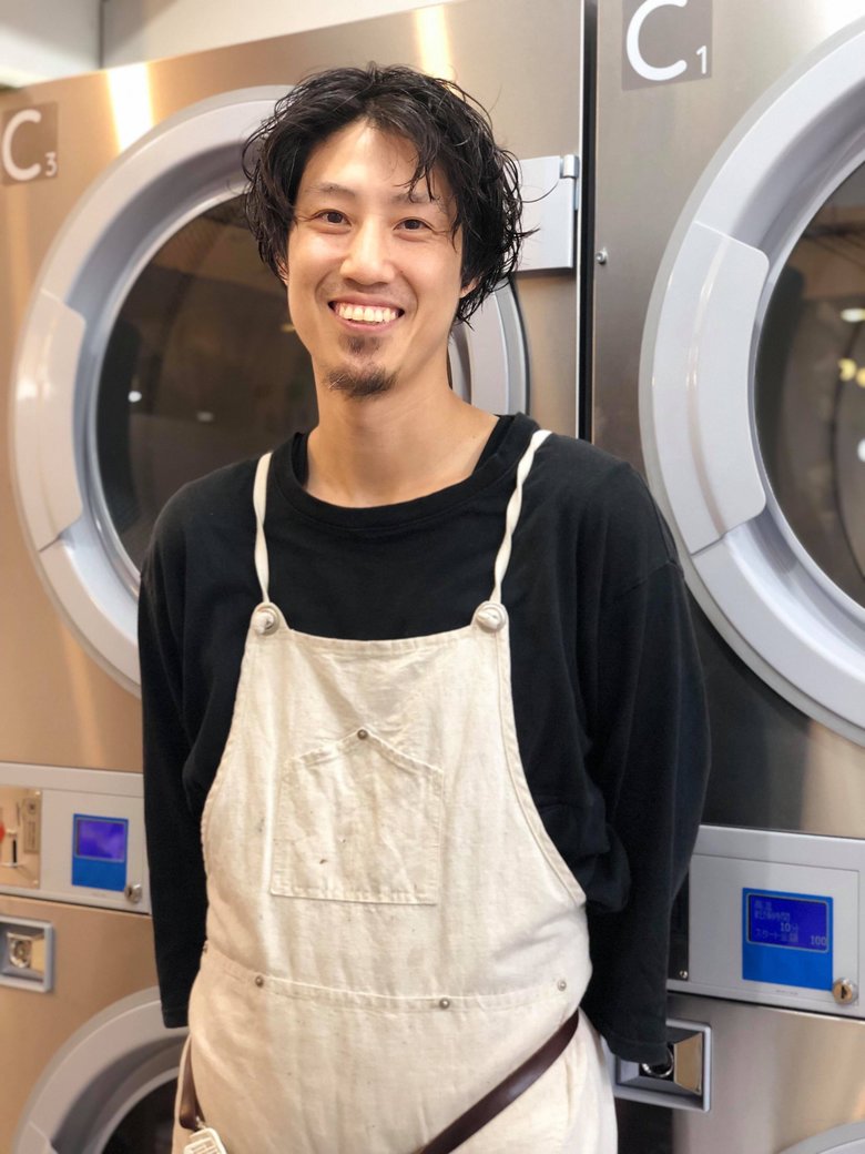 ランドリーの前に笑顔で立つ濱田さん