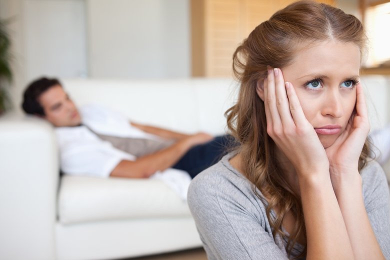 Sad looking woman with man on the couch behind her