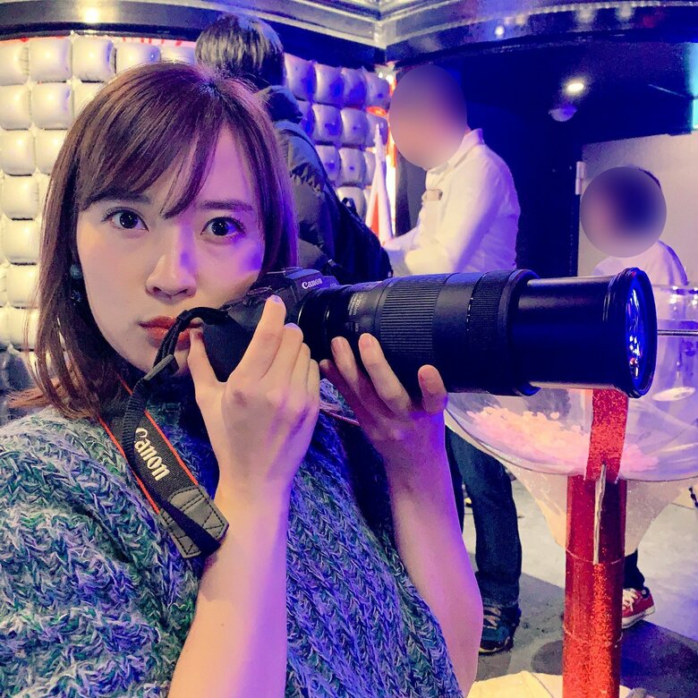 大きなレンズのついたカメラを持って取材するフリーランスライター時代の大木さん