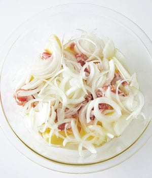 直径26㎝の耐熱ボウルに、水けをきった新じゃが、豚肉、玉ねぎの順に広げ入れる。混ぜたBを加え、ふんわりラップをかけて600Ｗの電子レンジで20分加熱する。