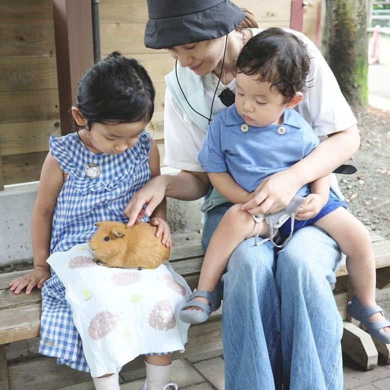 娘さんの膝に乗せた小動物と親子で触れ合う吉田明世さん