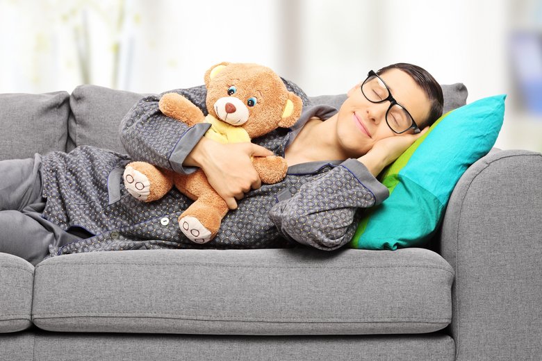 Young man holding teddy bear and taking a nap