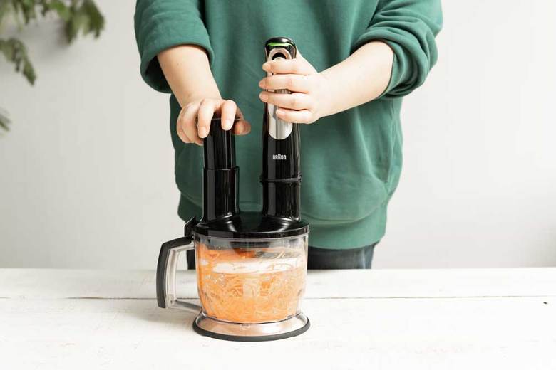 ▲ボウルに「せん切りツール」をセットし、食材投入口からにんじんを入れて、本体のスイッチを入れる。