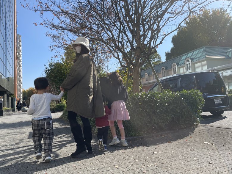 白い帽子を被り後ろを振り返る加藤さん。3人の子どもと買い物中