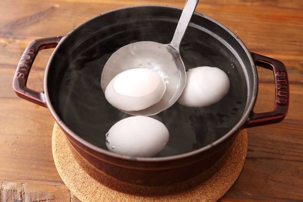 お玉で鍋に卵を入れるところ