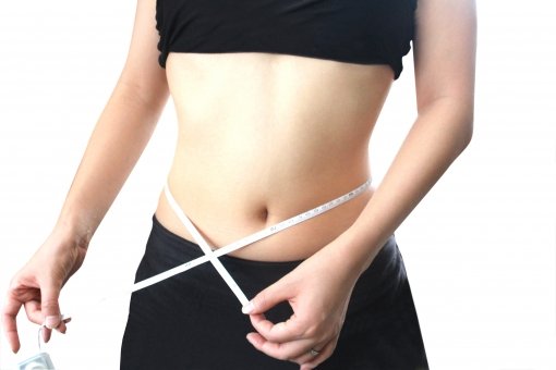 腹筋で痩せた下腹のサイズを図る女性の画像