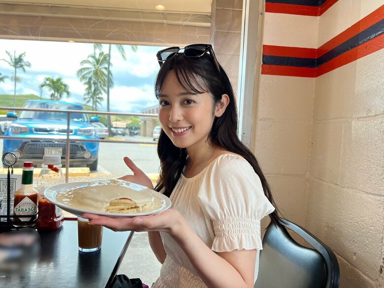 休暇中のハワイでマカダミアナッツソースのパンケーキを前に笑顔の久慈さん