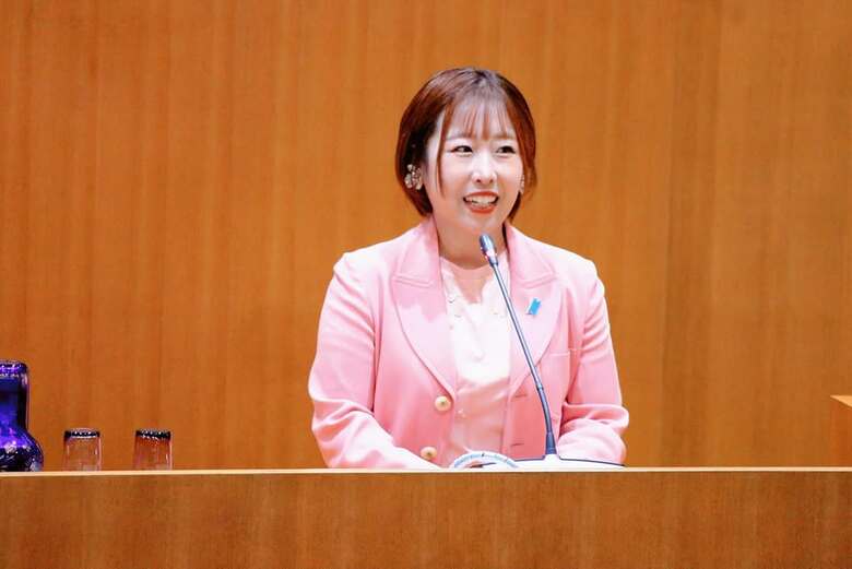 テーマカラーのピンクのスーツで議会で発言する夏目さん
