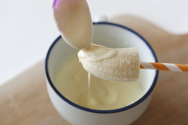 バナナを半分に切り、ペーパース トローをさしこむ。レンジで溶か したホワイトチョコを下写真のようにスプーンでかけて、冷蔵庫で冷やし固める。チョコペンで顔を描いたら、かわいいオバケに。「ホワイトチョコをしっかり固めてからでないと、チョコ ペンが混ざって汚くなるので注意」
ホワイトチョコは冷めると固くなるので、熱いうちに一気にかけて。