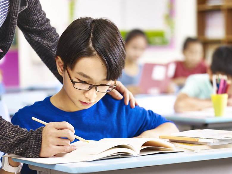 asian pupil getting help from teacher in class