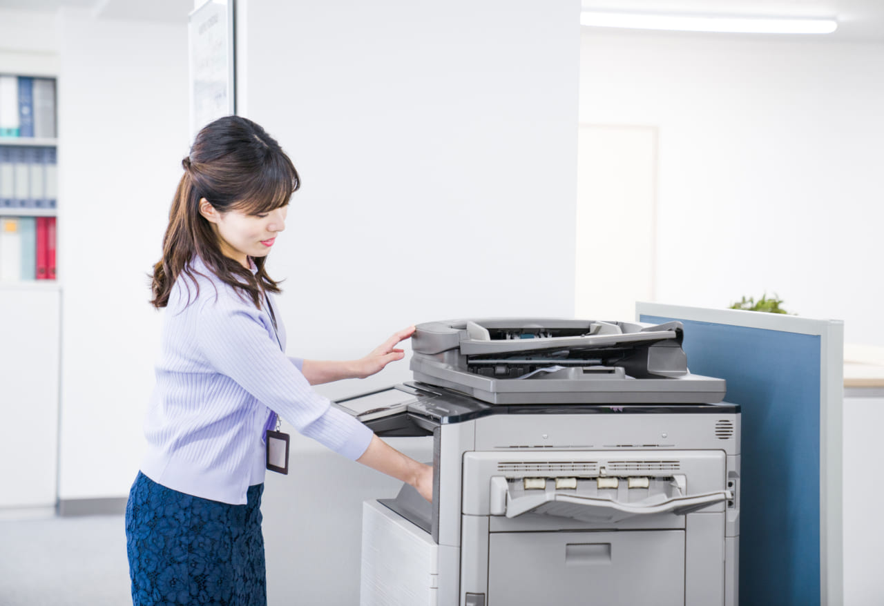 会社でプリントアウトする女性