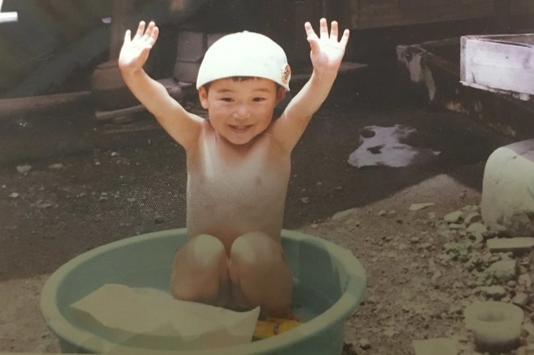 タライで水遊びをする幼少期の佐藤さん
