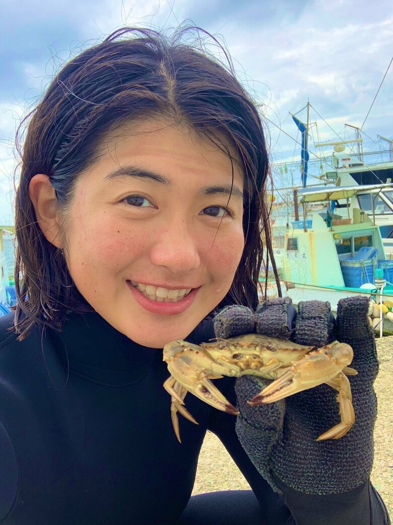 自分で獲ったカニを手に笑顔の本田さん