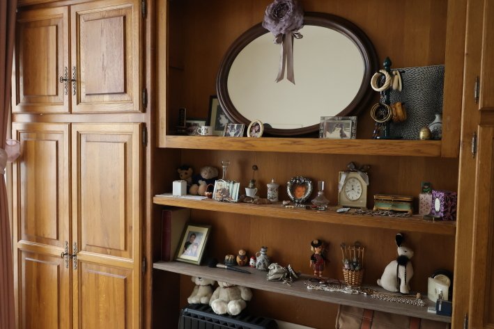 ベッドルームの棚。旅先で出合った小物や家族との写真といった思い出を飾っている