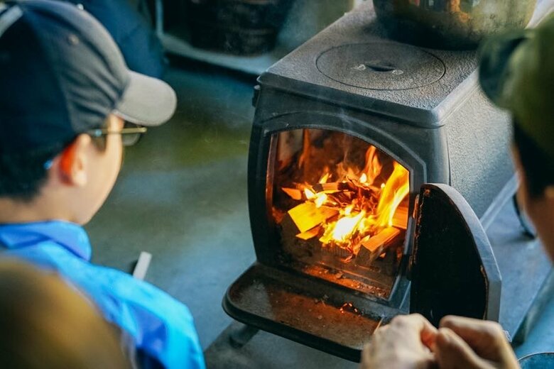 薪をくべる子ども。慣れない作業に緊張も